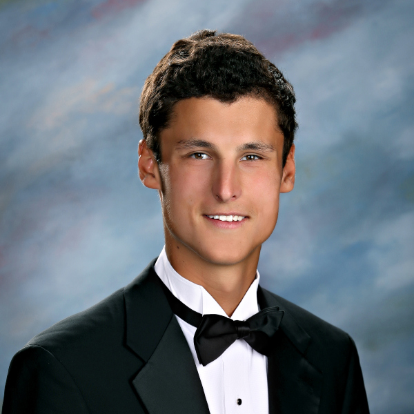 A young man in a black tuxedo poses for a formal portrait, capturing the tradition of St. Paul’s School on the Northshore.
