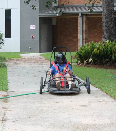 A person in a helmet and harness drives a go-kart on campus at St. Paul's School, one of the top private schools on the Northshore.