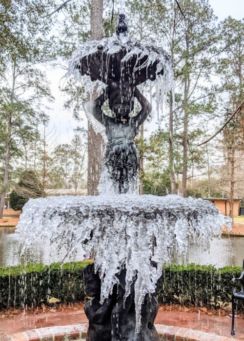 A two-tiered outdoor fountain at St. Paul's School is frozen in motion, surrounded by trees and a pond on the Northshore.