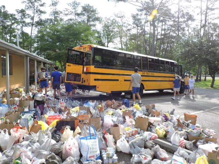 A group unloads groceries and supplies from a yellow school bus, reminiscent of community efforts at St. Paul’s School on the Northshore.