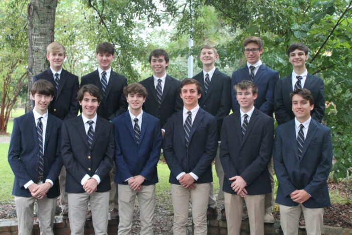 Thirteen young men in blazers and ties from St. Paul's School pose outdoors, representing a leading private school on the Northshore.