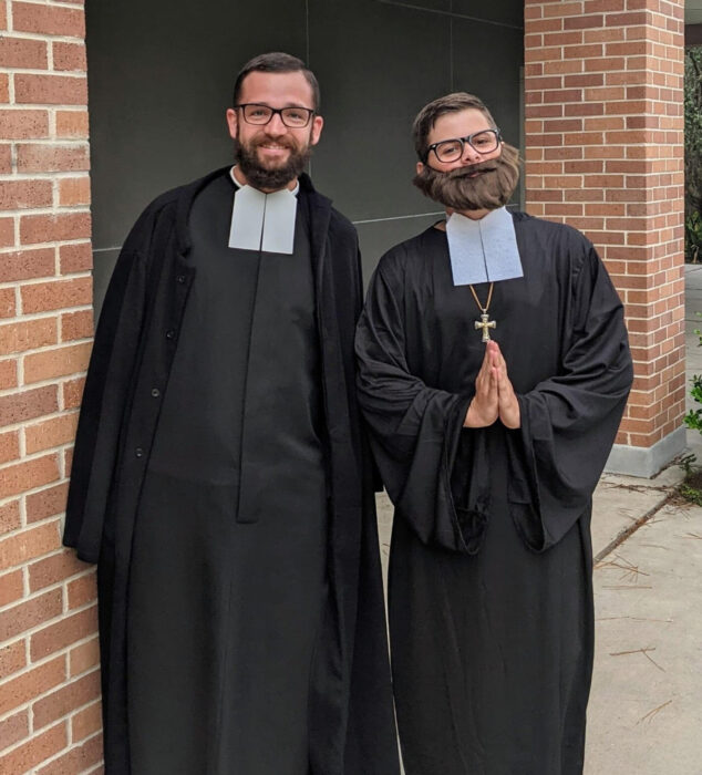 Two people in black religious robes and glasses stand side by side, reflecting the tradition of St. Paul's School on the Northshore.