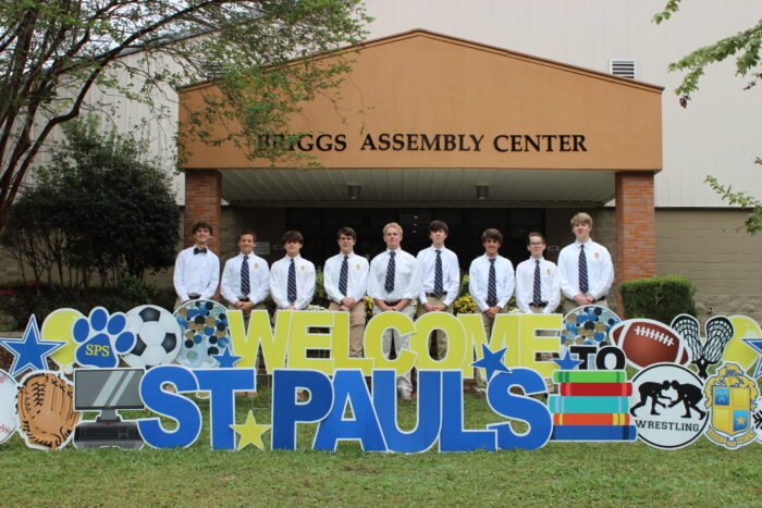 Nine students in white shirts and ties sit on a wall at St. Paul's School, a leading school for boys northshore LA, with a 