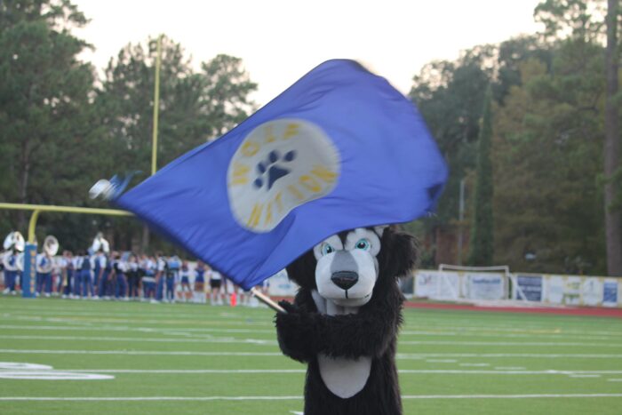 A wolf mascot waves a blue 