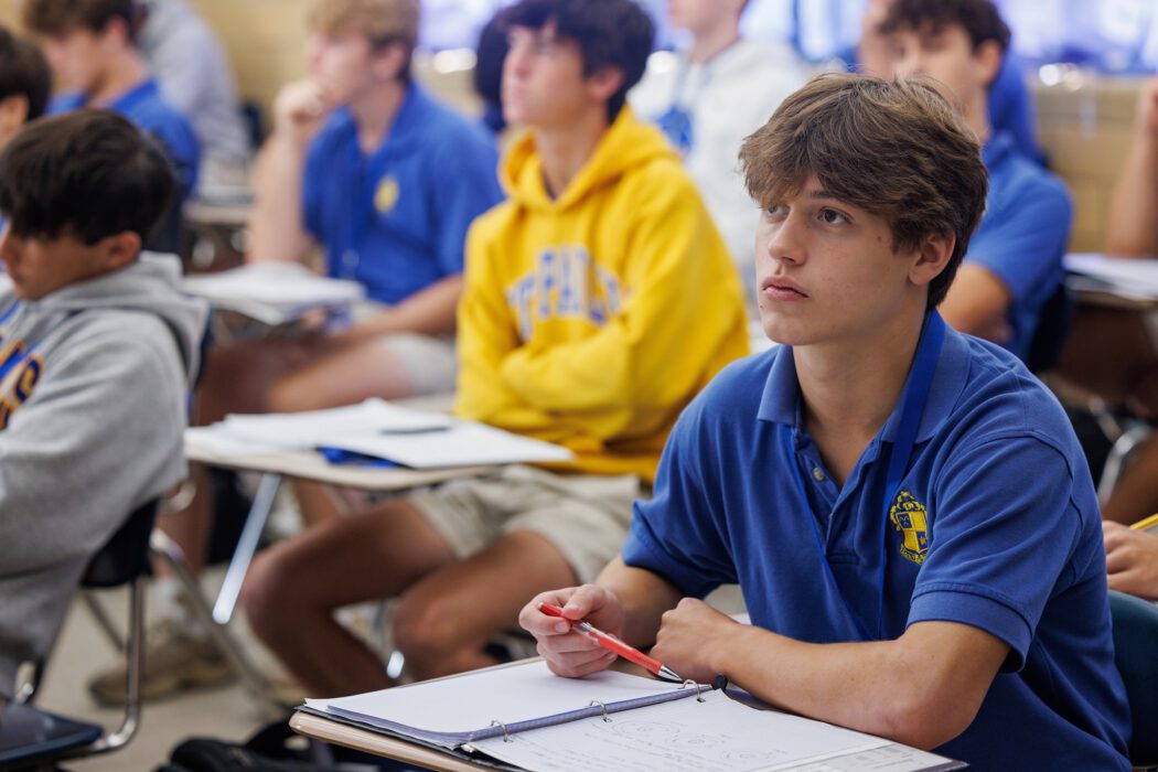 Male students in uniform at St. Paul's School sit attentively at desks, taking notes in this private school on the Northshore.