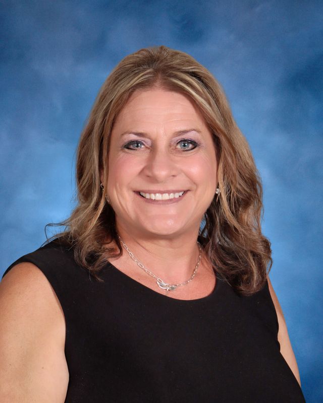 Smiling woman with shoulder-length light brown hair in a sleeveless black top, in front of a blue background at St. Paul's School.