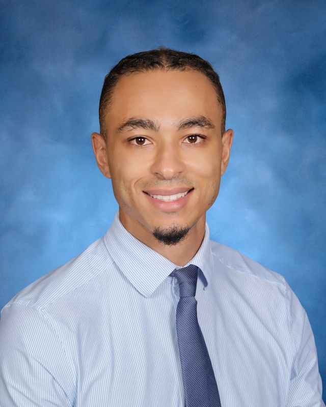 A man with short hair and a goatee smiles, dressed in a tie, representing St. Paul's School for boys on the Northshore, LA.