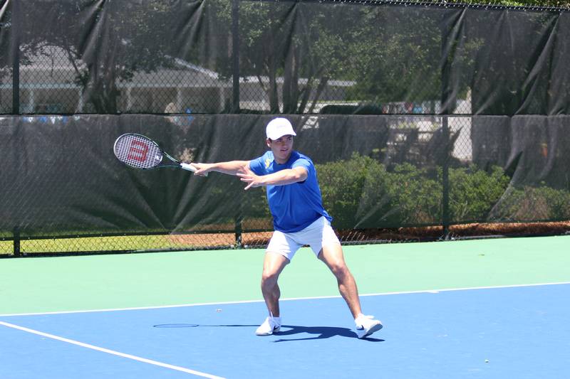 A person in a blue shirt and white cap prepares to hit a tennis ball at St. Paul's School, a top private school on the Northshore.