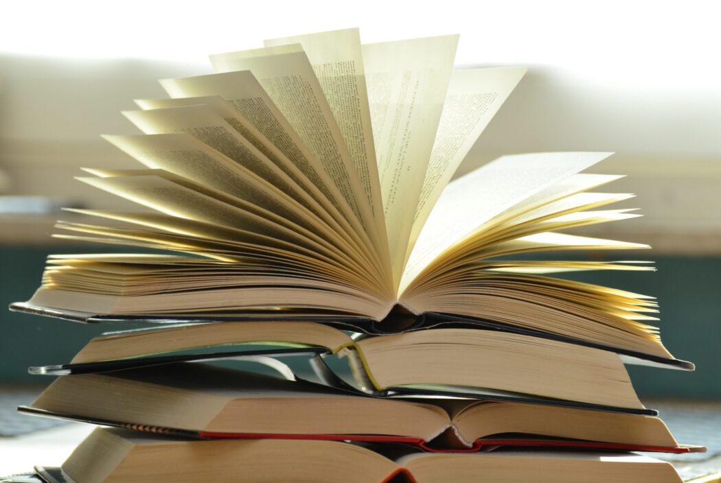 A stack of open books is shown at St. Paul's School, a top school for boys Northshore LA, with pages flipping upwards in bright natural light.