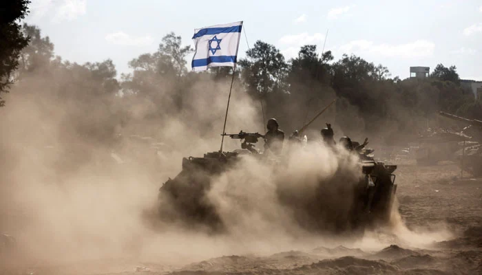 An armored vehicle with an Israeli flag moves through a dusty landscape, highlighting the crossfire of the Israeli-Palestinian Conflict.