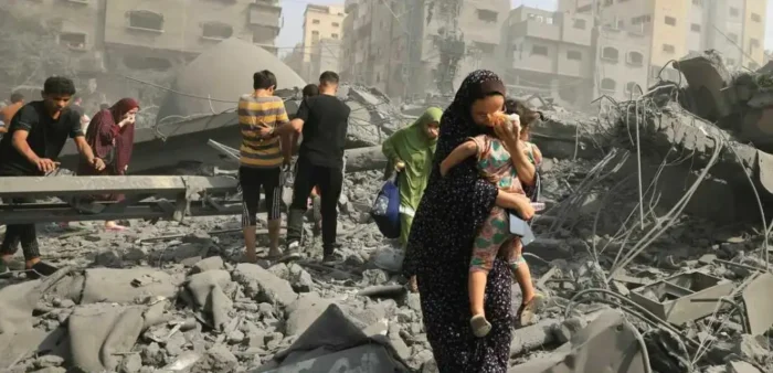 People walk through rubble and debris of destroyed buildings, caught in the crossfire of the Israeli-Palestinian conflict.