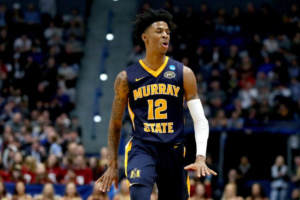 Basketball player in a Murray State uniform with number 12 gestures on the court, inspiring young basketball players as spectators watch.