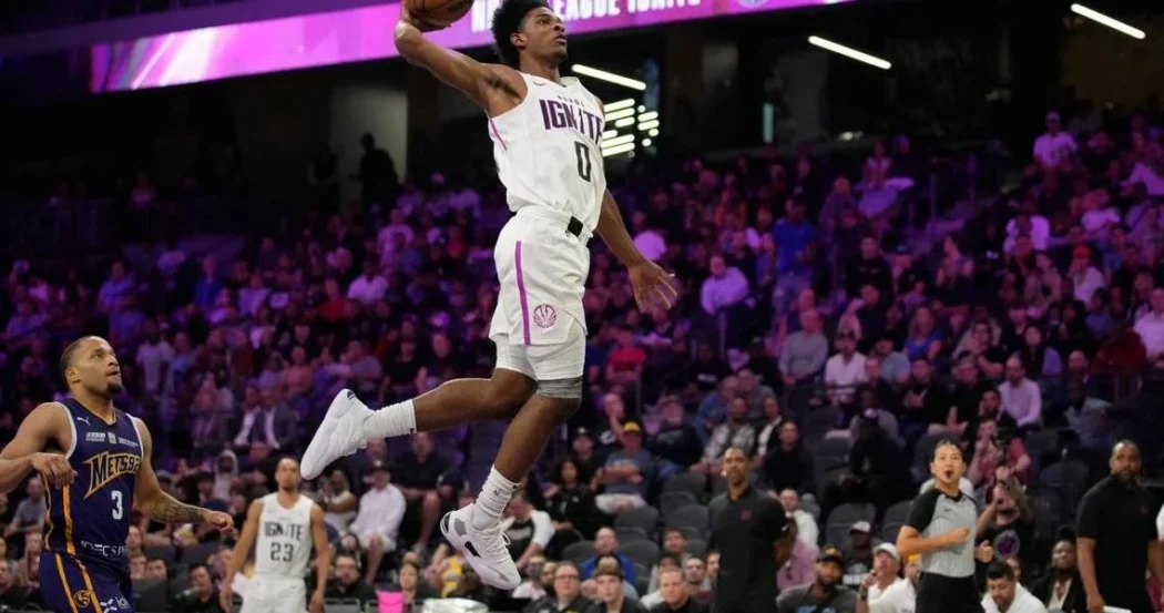 A young basketball player in a white uniform leaps for a dunk, showcasing talent reminiscent of G League Ignite prospects.