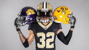 A football player in a black and gold uniform previews the 2024 season, holding two LSU helmets against a plain background.