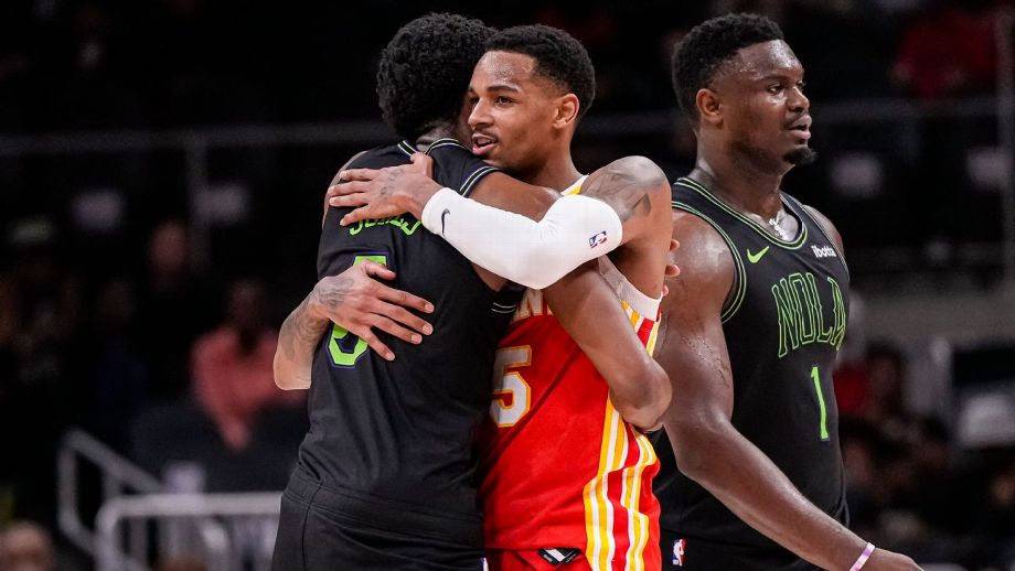 Two basketball players hug after a game as another stands nearby, all sporting different uniforms including the New Orleans Pelicans.