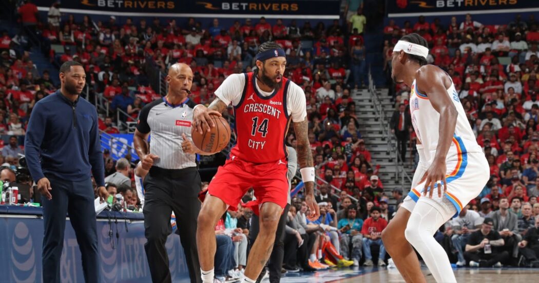 A basketball player in red dribbles against a defender as fans watch, highlighting the intensity of the Pelicans 2024-25 season.
